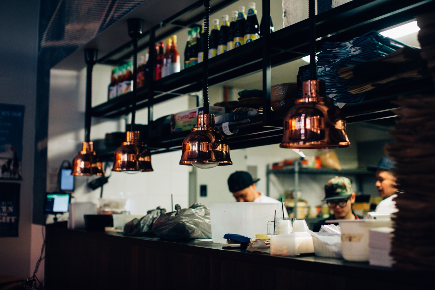 Koks aan het werk achter de keukenpas onder koperen lampen