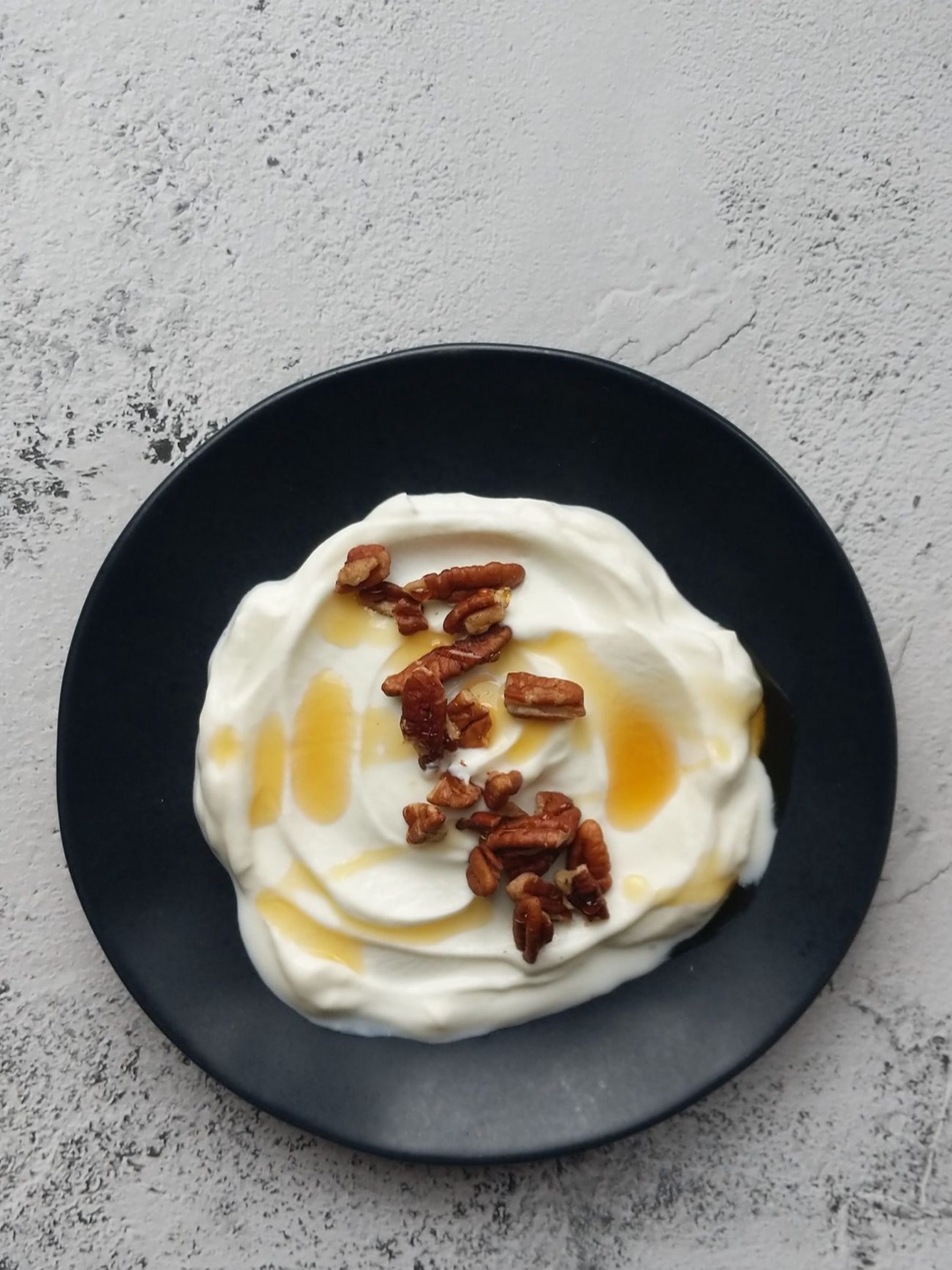 Stracciatella met honing en geroosterde pecannoten op een donker bord