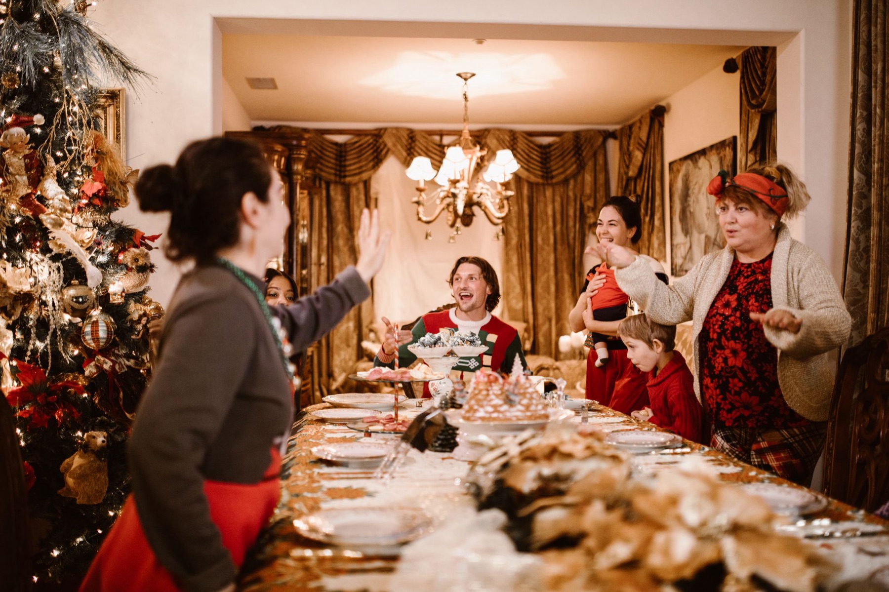Gasten aan een lange, feestelijk gedekte tafel bij kaarslicht